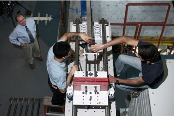 aerial view of professor observing 2 students working with research machine