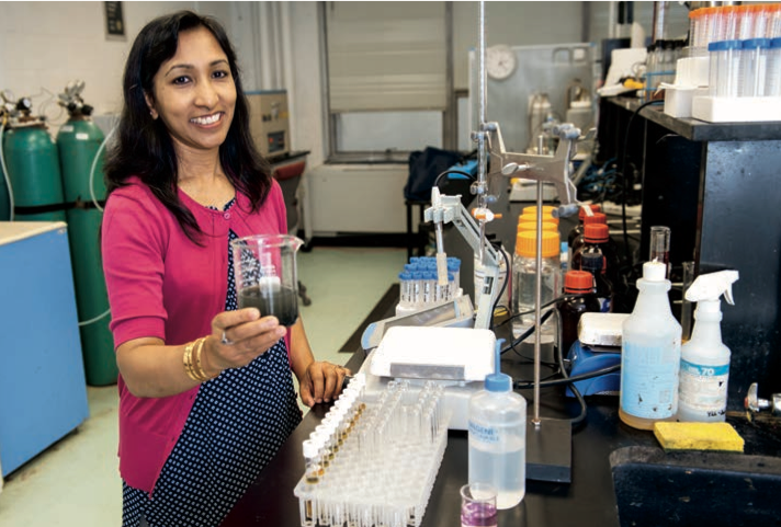 Prof. Rumana Riffat in lab holding jar of wastewater