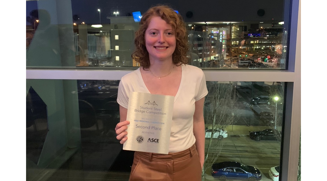 student posing with 2nd place plaque