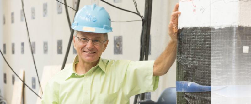 Professor leaning against wall in the highbay