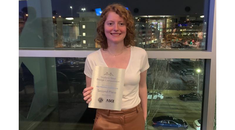 student posing with 2nd place plaque